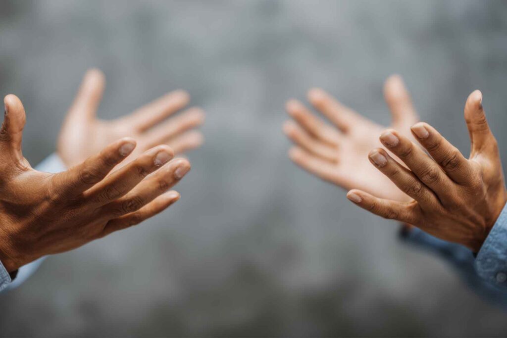 Two people face each other with extended hands.