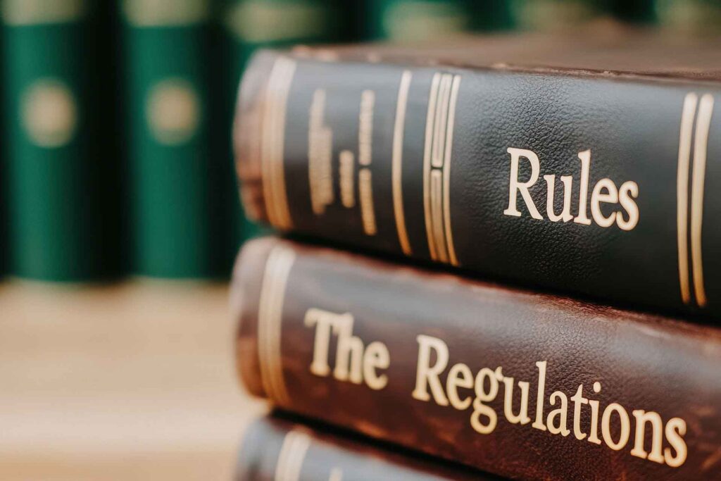 Books titled "Rules" and "The Regulations" stacked on their sides